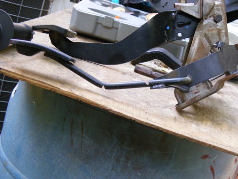 1978 Ford Bronco - Close-up of a vehicle's pedal assembly, showing metal and plastic parts on a workbench.
