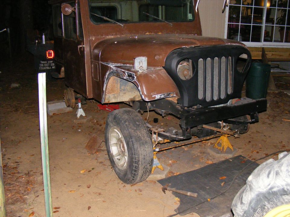 Brown Jeep CJ-5 on jack stands, front end disassembled