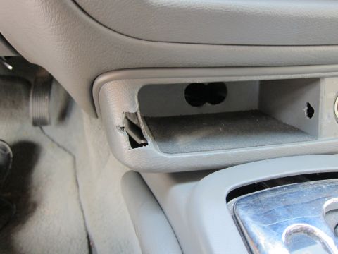 2001 Ford Crown Victoria - Interior view of a gray dashboard compartment showing damaged trim and two circular openings, consistent with a 2001 Ford Crown Victoria.