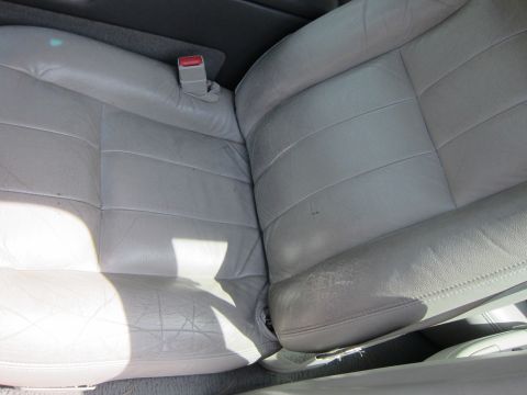2001 Ford Crown Victoria - Interior view of worn leather car seats, showing creasing and bolster wear.