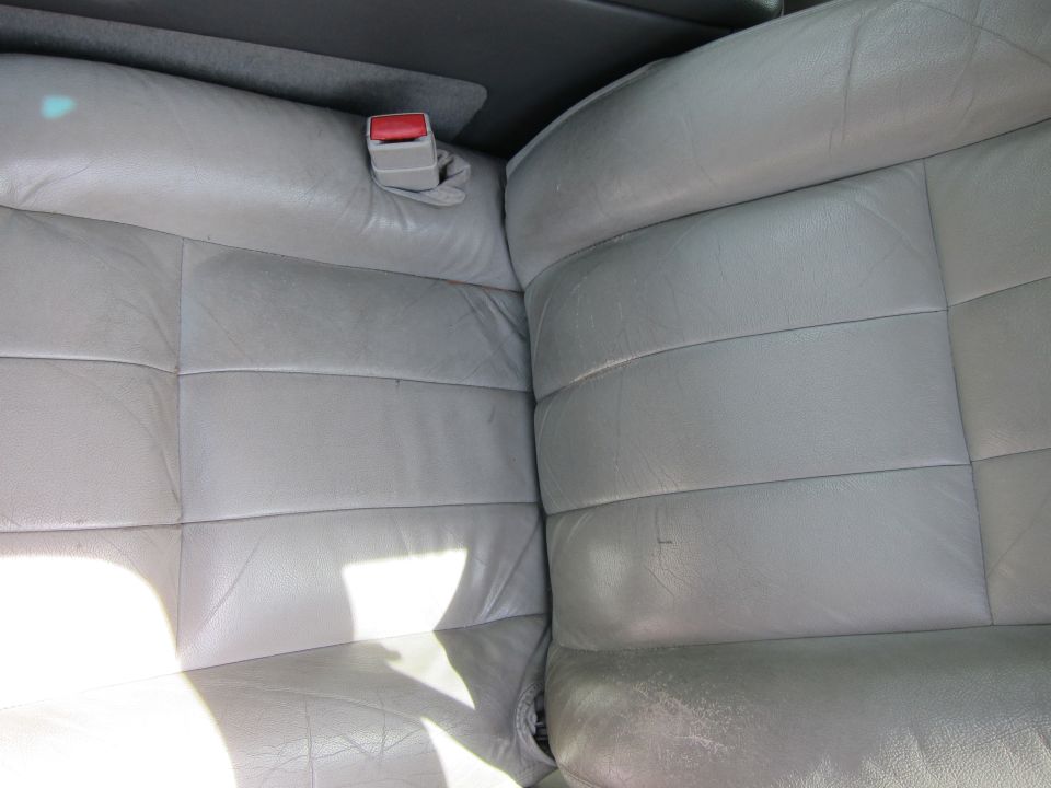 close-up of gray leather car seats with a red seatbelt buckle visible