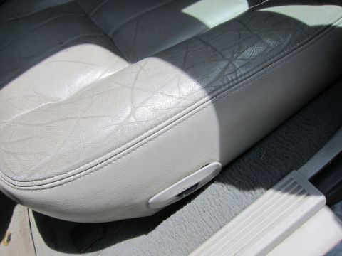 2001 Ford Crown Victoria - Close-up of a car's interior showing a worn leather seat and carpeted floor.