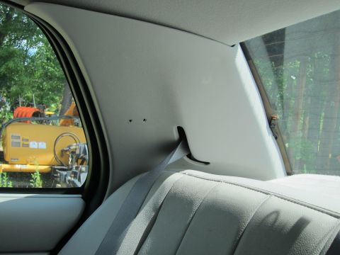 2001 Ford Crown Victoria - Interior view of a car's rear passenger side pillar and seat, with a yellow construction vehicle visible through the window.