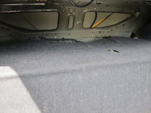 2001 Ford Crown Victoria - The interior of a car trunk shows exposed metal framing and gray carpeting.