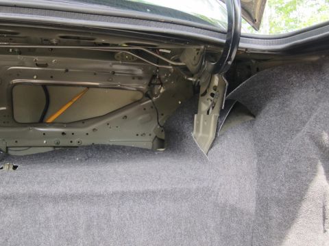 2001 Ford Crown Victoria - The interior of a car's trunk is visible, with grey carpeting and exposed metal structure.