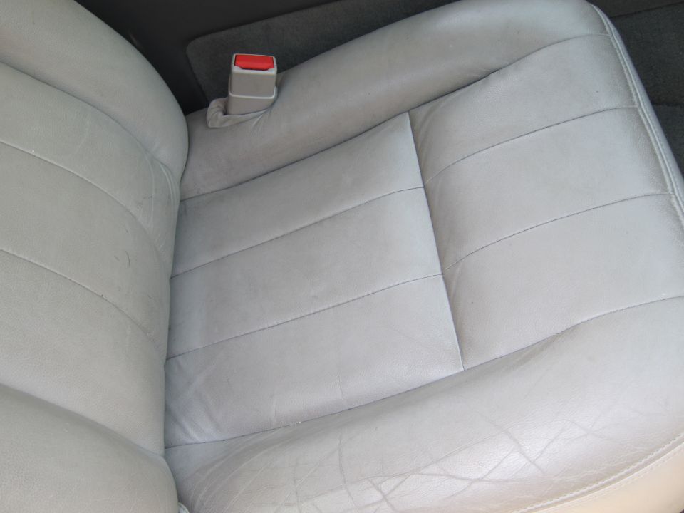 Light gray leather car seats with a red seatbelt buckle visible