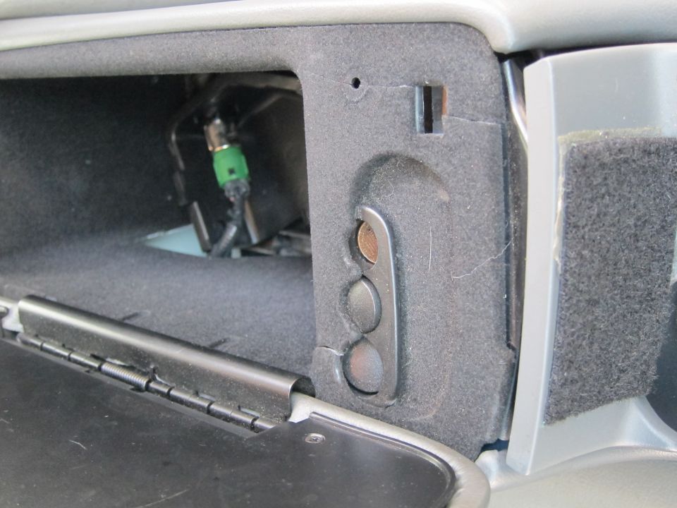 Interior of a car's glove box showing wiring and a green connector