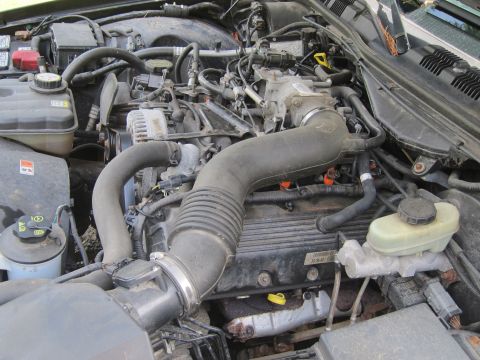 2001 Ford Crown Victoria - The engine bay of a 2001 Ford Crown Victoria is visible, with various components like the alternator and air intake clearly depicted.