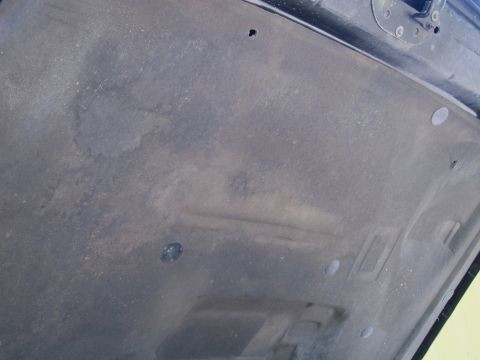 2001 Ford Crown Victoria - The underside of a car hood shows dust accumulation and some water stains.