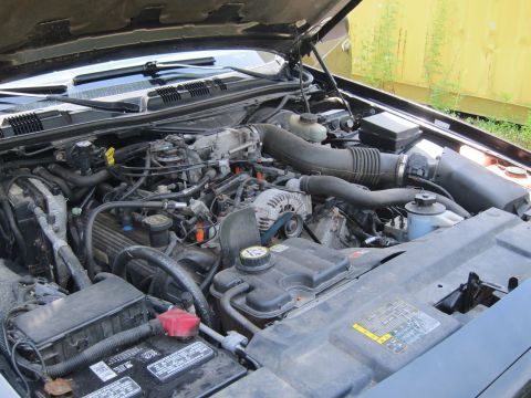 2001 Ford Crown Victoria - The engine bay of a 2001 Ford Crown Victoria is visible with the hood open, revealing the V8 engine components.