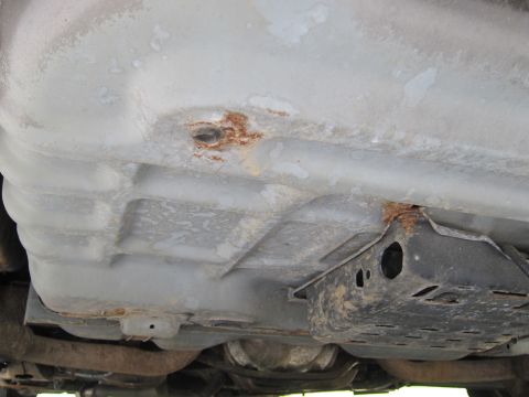 2001 Ford Crown Victoria - Close-up view of the undercarriage of a vehicle, highlighting the fuel tank and signs of rust.