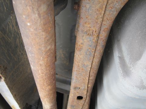 2001 Ford Crown Victoria - Close-up view of heavily rusted undercarriage components, including exhaust pipes and frame elements.