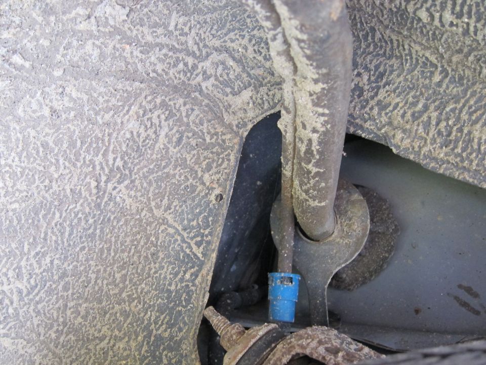 Close-up of underbody part with blue connector and metal tubing
