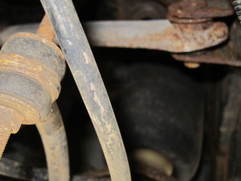 2001 Ford Crown Victoria - Close-up view of aged and rusty suspension parts with a rubber hose.