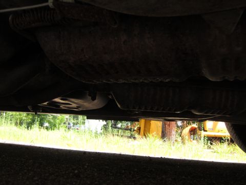 2001 Ford Crown Victoria - The underside of a vehicle, showing the exhaust system and various components. Background features grassy area and yellow machinery.