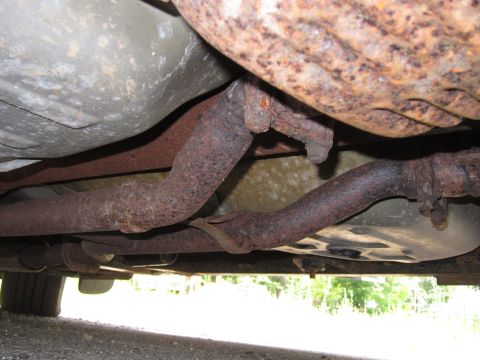 2001 Ford Crown Victoria - The underside of a vehicle shows significant rust on its exhaust system components.