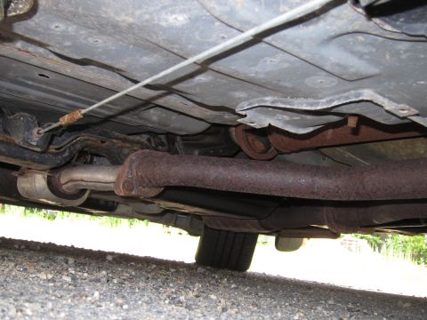 2001 Ford Crown Victoria - The undercarriage of a vehicle displays significant rust on its exhaust system and other mechanical parts.