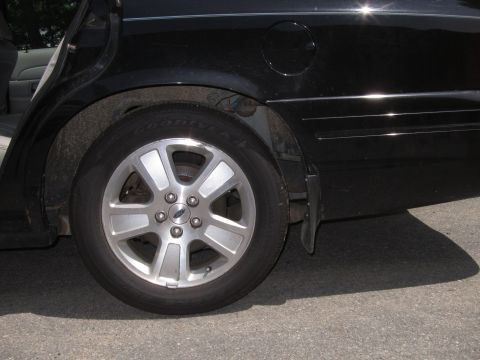 2001 Ford Crown Victoria - The rear side of a black 2001 Ford Crown Victoria is visible, focusing on the wheel and fender area.