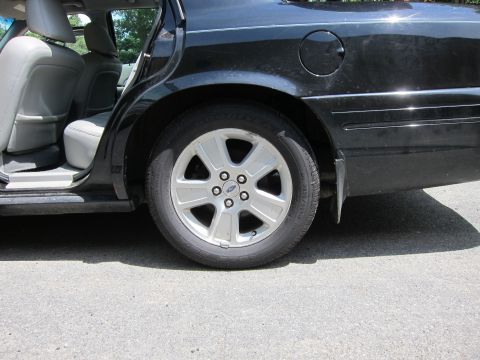 2001 Ford Crown Victoria - Rear passenger side view of a black 2001 Ford Crown Victoria, showing the interior and wheel.