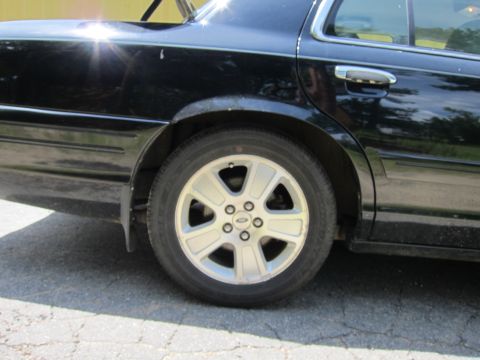 2001 Ford Crown Victoria - Rear quarter panel and wheel of a black 2001 Ford Crown Victoria sedan.