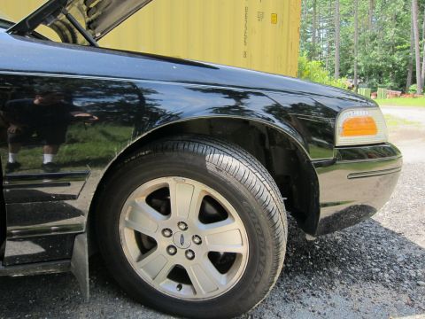 2001 Ford Crown Victoria - Close-up view of the front passenger side of a black sedan with the hood open.