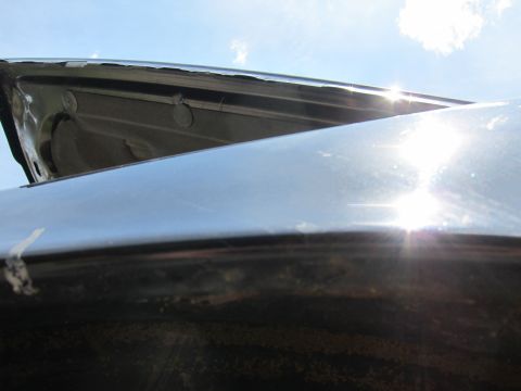 2001 Ford Crown Victoria - The edge of a car's hood shows wear and tear under a bright sky.