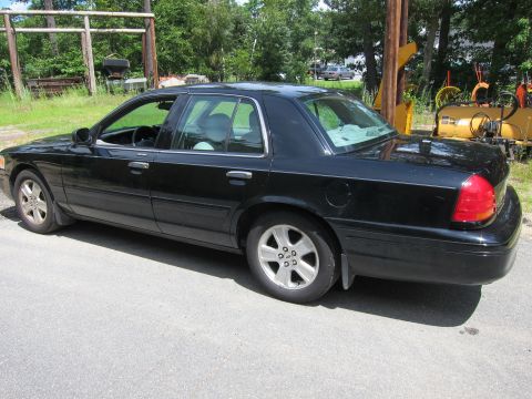 2001 Ford Crown Victoria - A black 2001 Ford Crown Victoria sedan is parked outdoors on an asphalt surface.