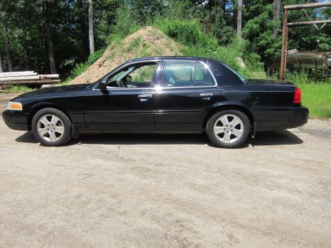 2001 Ford Crown Victoria - This black 2001 Ford Crown Victoria sedan is shown from the side, its distinctive body style and alloy wheels.