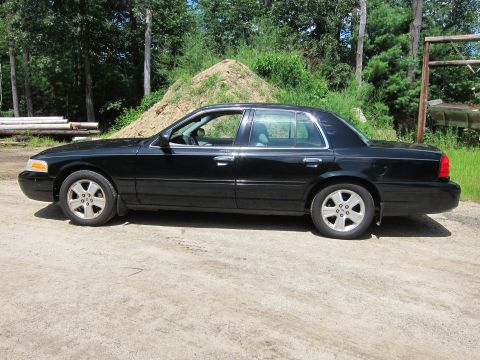 2001 Ford Crown Victoria - Side profile of a black 2001 Ford Crown Victoria sedan parked outdoors.