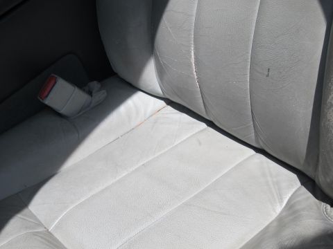 2001 Ford Crown Victoria - Close-up of the interior showing light-colored leather seats and a seatbelt buckle.