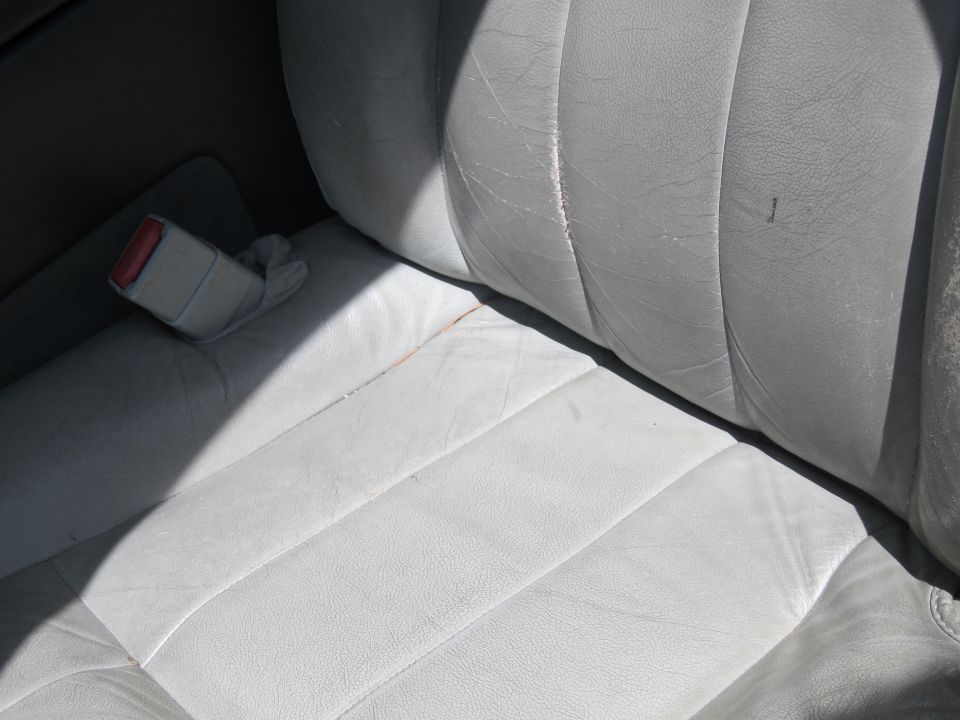 Interior view of light-colored leather seats with a seatbelt buckle