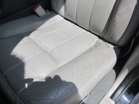 2001 Ford Crown Victoria - The interior of a vehicle shows light gray leather seats with visible wear and a seatbelt.