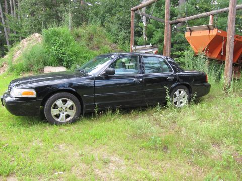 2001 Ford Crown Victoria - Side view of a black 2001 Ford Crown Victoria parked outdoors in a grassy area.