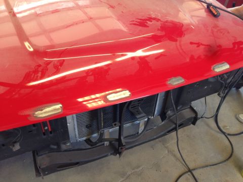 1964 Ford Fairlane - Close-up of a red car's front end, showing the hood and grille area with signs of recent repair work.