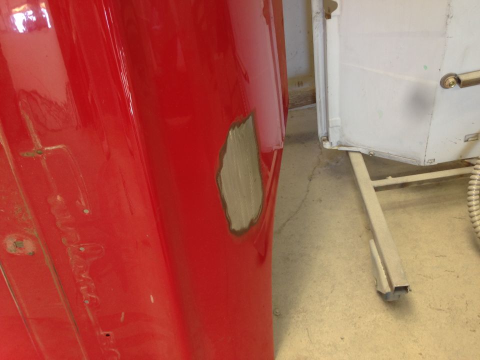 red car fender showing a patch of primer where bodywork is being done