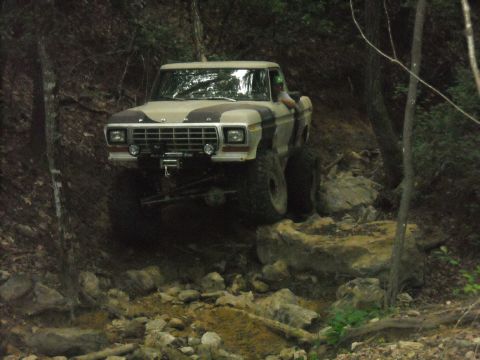 1979 Ford F-150 - Modified 1979 Ford F-150 truck tackling a challenging off-road course in a wooded area.