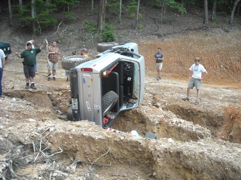 1979 Ford F-150 - A silver 1979 Ford F-150 pickup truck is overturned in a ditch, with onlookers observing the scene.
