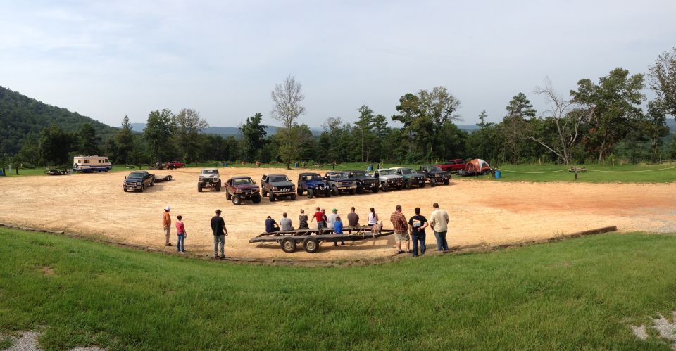 Group of people gathered around a trailer with several SUVs and trucks parked in the background
