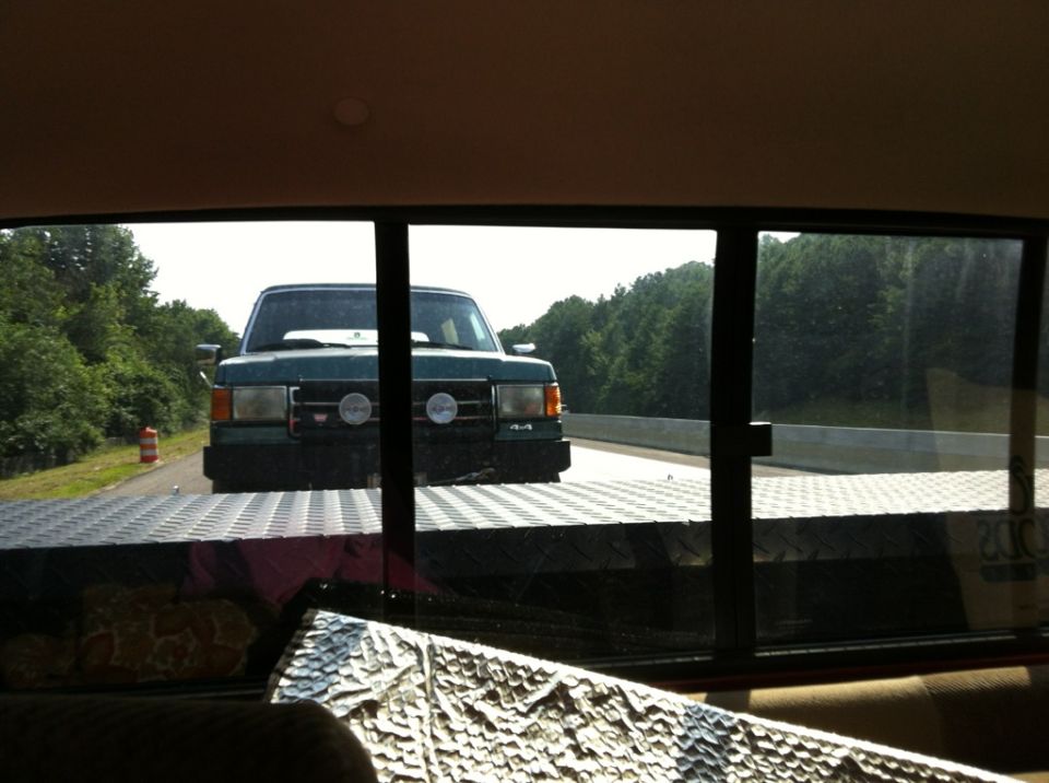 Green Ford F-Series truck with dual headlights and 4x4 badge, seen from a trailer