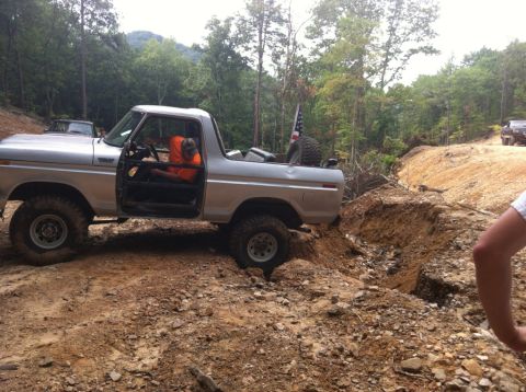 1989 Ford Bronco - A silver Ford Bronco navigates a challenging off-road course with a driver in an orange shirt.