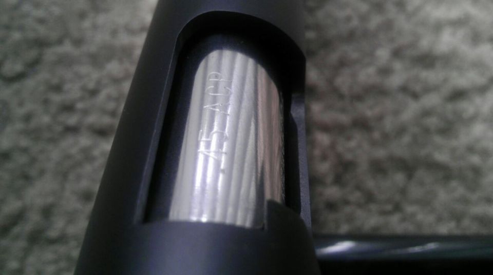 Close-up of a gun barrel showing "45 ACP" caliber marking