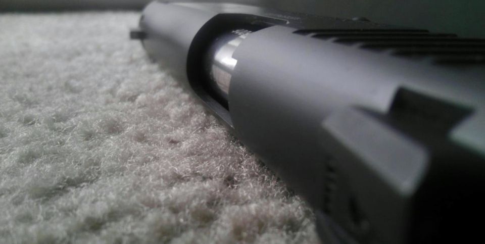 Close-up of a pistol slide and barrel resting on a textured surface