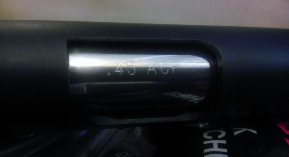 Close-up of a firearm slide showing '.45 ACP' marking