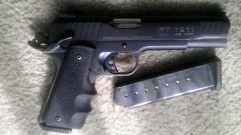 2000 Mercury Grand Marquis - A Taurus PT 1911 pistol chambered in .45 ACP is shown with its magazine on a carpeted surface.