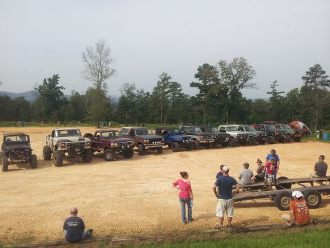 2013 Ford Bronco - A group of off-road vehicles are parked in a dirt lot with people gathered around.