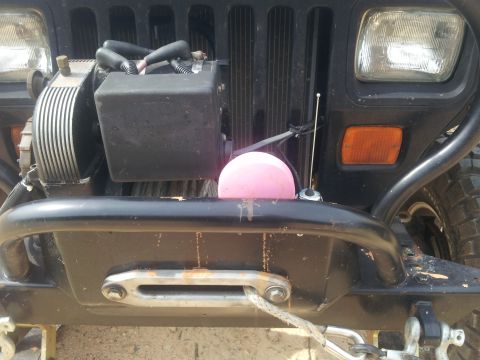 2013 Ford Bronco - The front of a Jeep Wrangler is shown, a winch and an aftermarket bumper with a pink accessory.