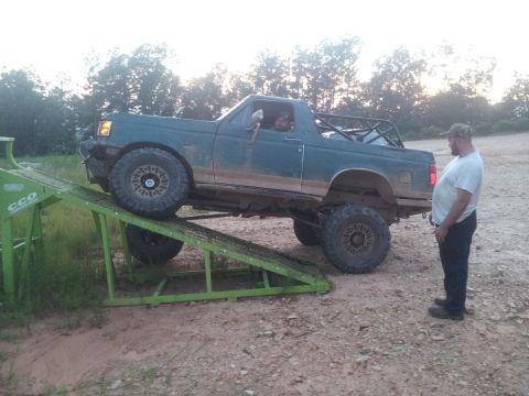 2013 Ford Bronco - A man watches a green Ford Bronco with a roll cage ascend a green ramp.