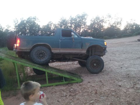 2013 Ford Bronco - Modified SUV with a roll cage and oversized tires navigates a ramp in an outdoor setting.