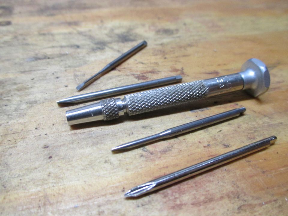 Set of precision screwdrivers with interchangeable bits on a wooden surface