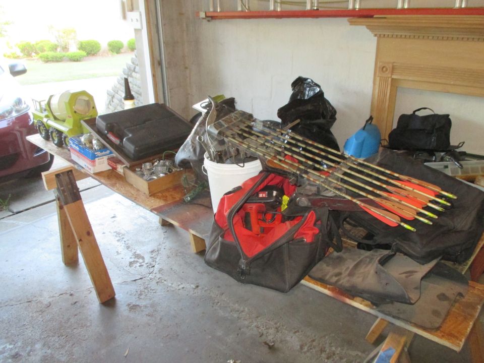 Garage scene with a toy cement mixer, tool case, archery equipment, and bags on a workbench